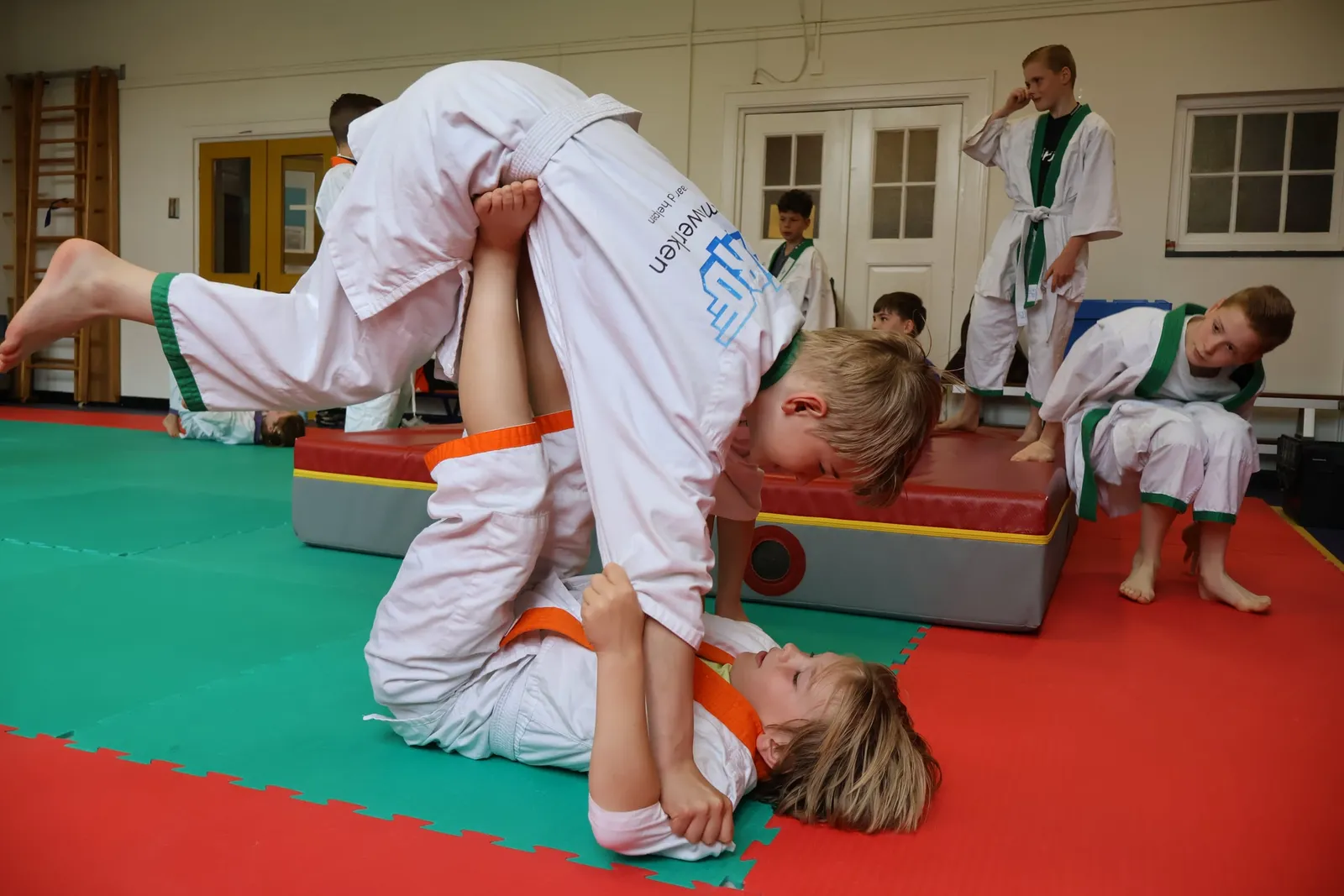 Kinderen oefenen samen een judoworp tijdens een les van HiRO